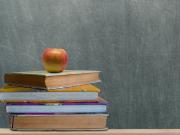 books and apple in front of blackboard