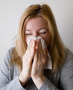 Woman blowing her nose. The common cold is just one of many diseases caused by viruses.  How does a tiny virus cause cold symptoms?