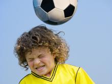 child hitting soccer ball with head